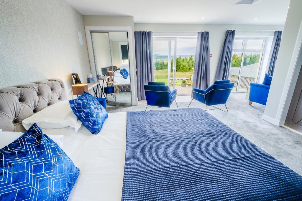 a bedroom with a large bed and blue chairs at Mingarry Park in Acharacle