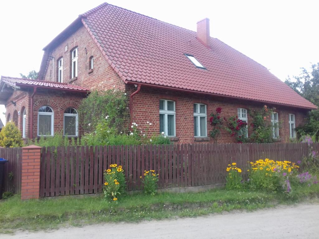 a red brick house with a fence and flowers at Wczasy na Kaszubach in Górki