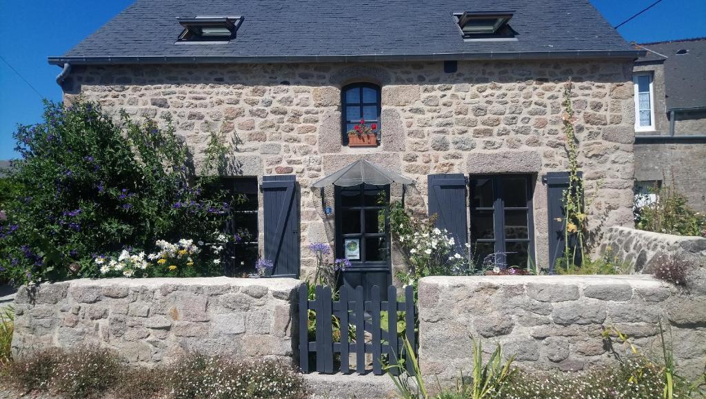 una casa de piedra con una puerta delante de ella en Entre terre et mer en Montfarville