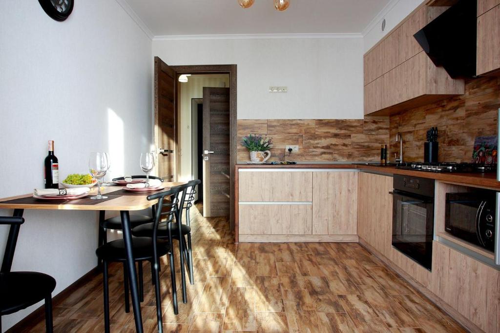 kuchnia z drewnianymi szafkami i stołem z krzesłami w obiekcie Apartament Vasilya Porika 48 Street Vinnytsya,Ukraine w mieście Winnica