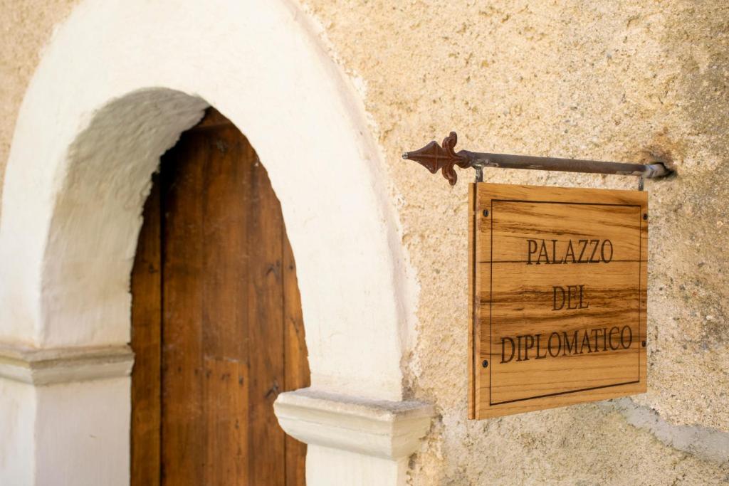 ein Holzschild an der Seite eines Gebäudes mit einer Tür in der Unterkunft Palazzo del Diplomatico in Belmonte Calabro