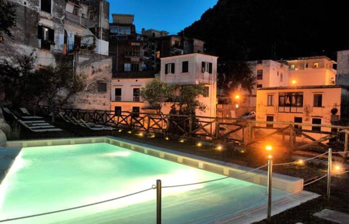 a large swimming pool in a city at night at Cartiera Apartment with Pool by AMALFIVACATION in Amalfi
