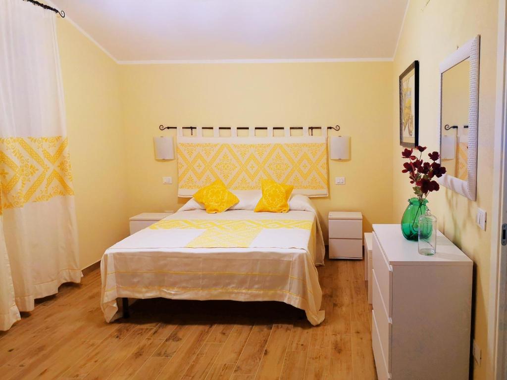 a bedroom with a bed with yellow walls and wooden floors at Le Orchidee in Bosa