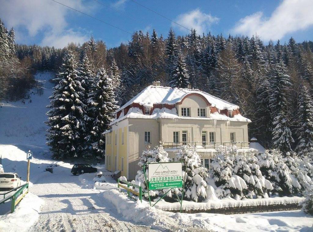 a house covered in snow with a sign in front at Horská Chata Pod Lanovkou in Jáchymov