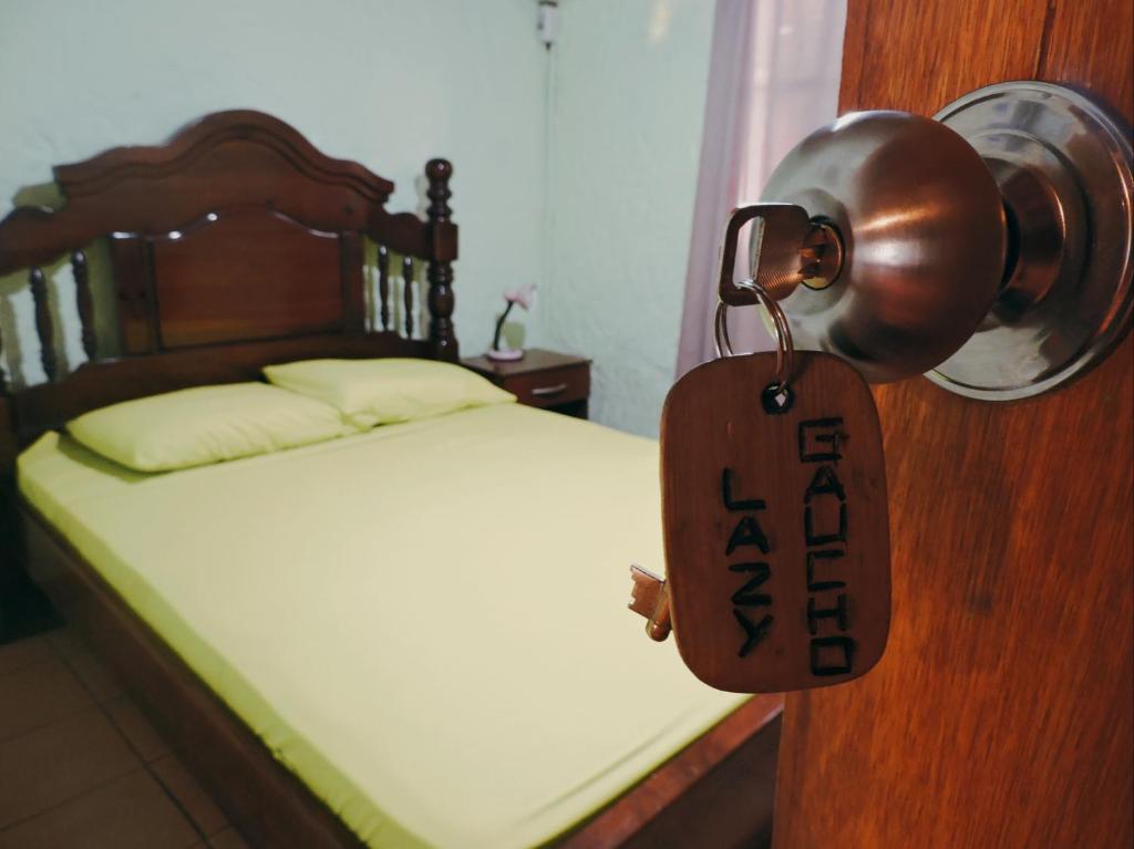 a bedroom with a bed with a wooden door with a tag on it at Hostel Lazy Gaucho in Paysandú