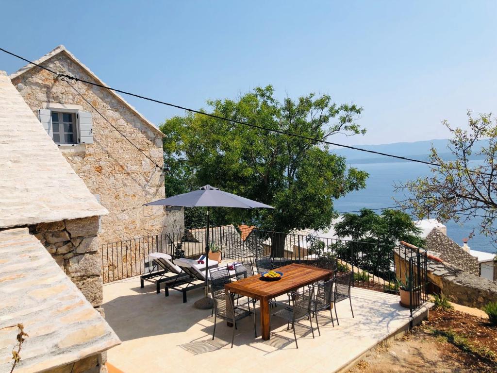 une terrasse avec une table et des chaises en bois ainsi qu'un parasol dans l'établissement Tom house, à Murvica