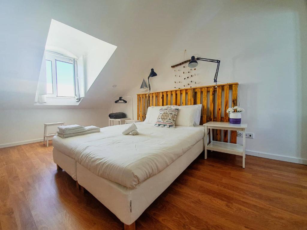 1 dormitorio con 1 cama grande y cabecero de madera en PÊPA Guesthouse, en Setúbal