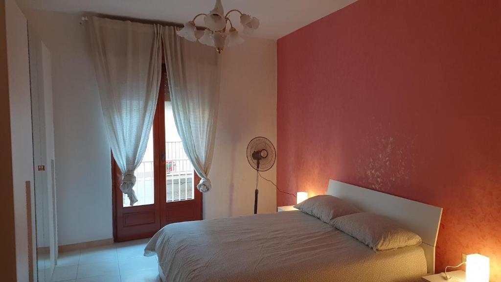 a bedroom with a bed and a red wall at Appartamento In Paese in Niscemi