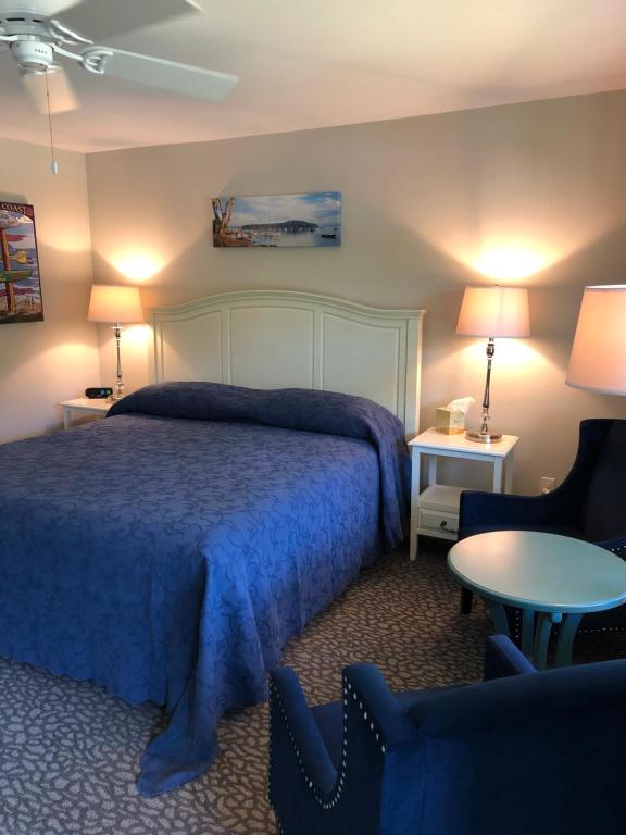 a bedroom with a bed and two chairs and a table at Island Place in Bar Harbor