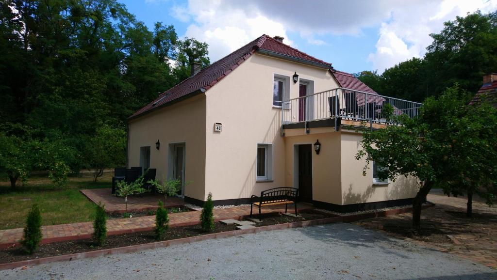 a small white house with a balcony and trees at Haus Waldidyll in Lauta
