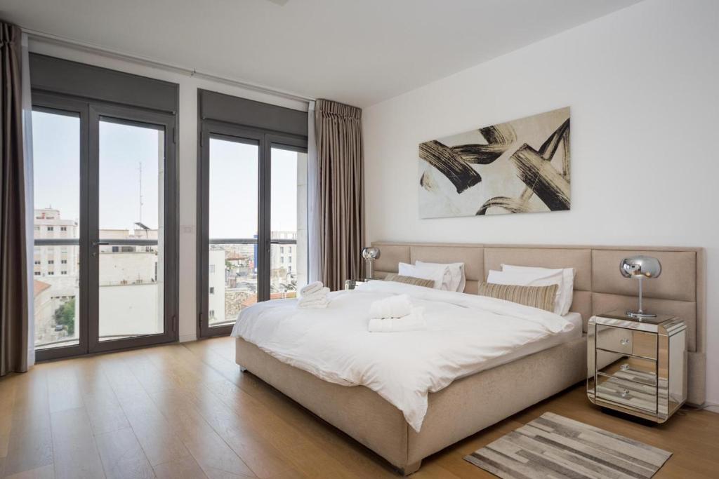 a white bedroom with a large bed and large windows at Rav Kook Luxury Complex - 4BDR in Jerusalem