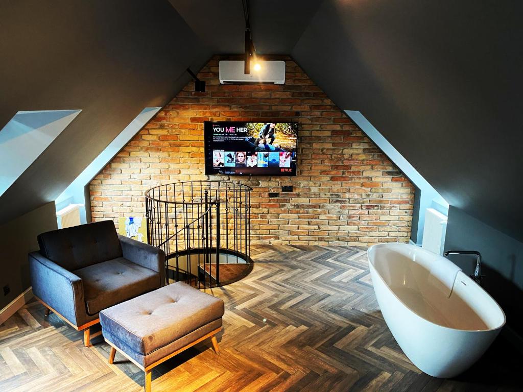 a bathroom with a tub and a chair and a tv at Old Town Luxury Apartments Zgorzelec in Zgorzelec