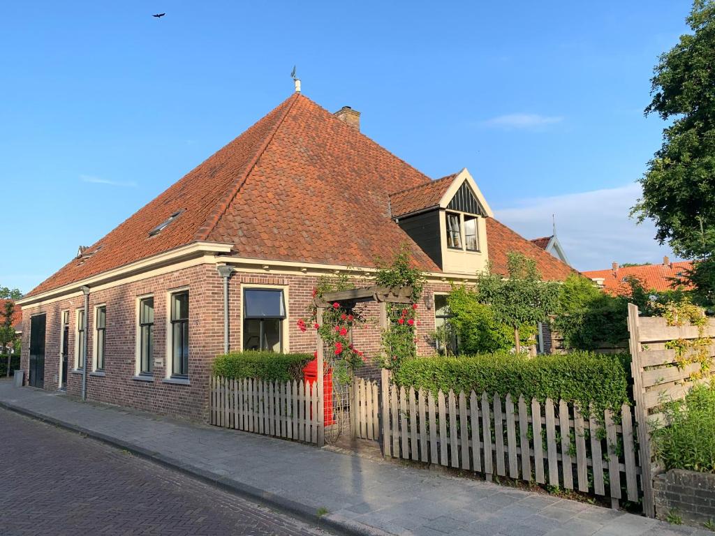 a brick house with a red door and a fence at "De Walvisch", appartement in authentieke boerderij in Edam