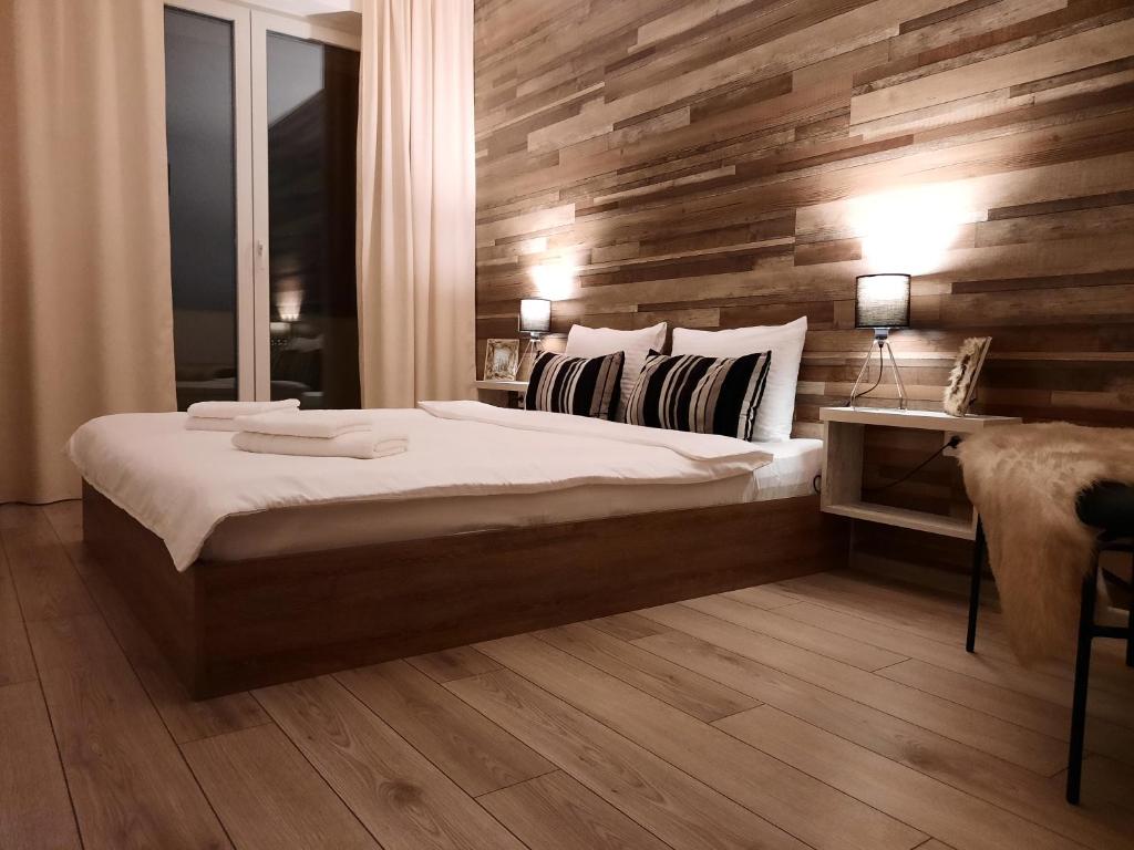 1 dormitorio con 1 cama grande y pared de madera en New Grey Residence Apartament, en Târgu Mureș
