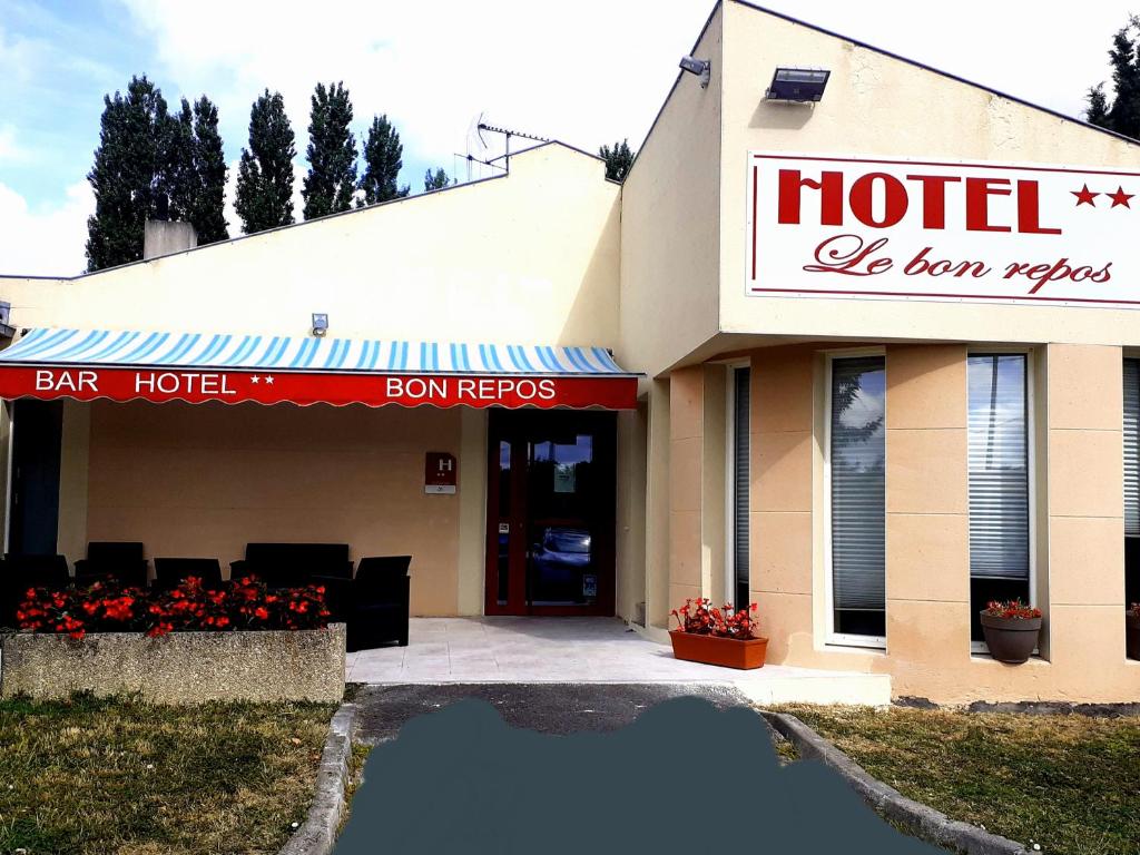 un edificio alberghiero con riflesso in una pozzanghera di fronte di Hôtel Bon Repos a Barbezieux-Saint-Hilaire