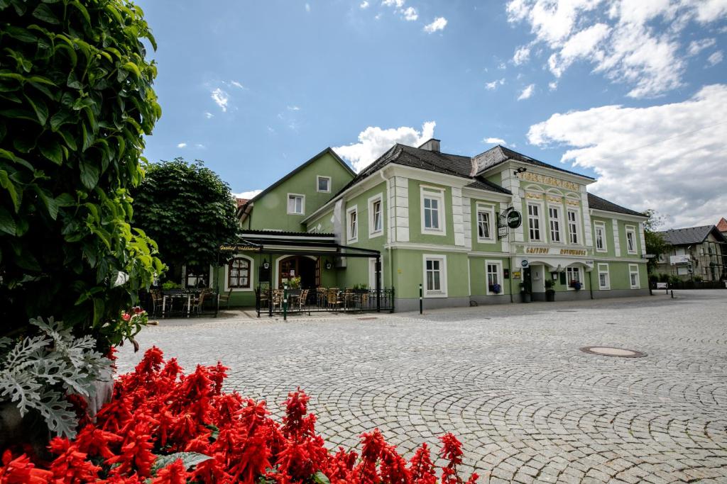 ein großes grünes Gebäude mit roten Blumen davor in der Unterkunft Gasthof Rothwangl Hannes in Krieglach