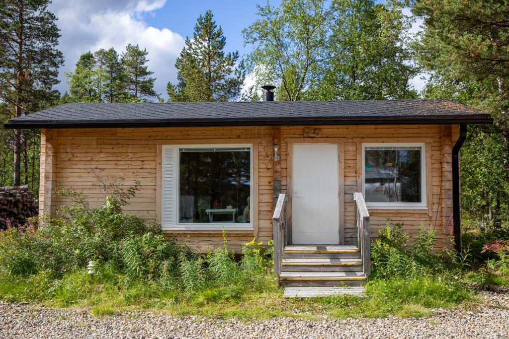 une petite maison avec une véranda et une porte blanche dans l'établissement Mökki - The White Blue Wilderness Lodge, à Inari