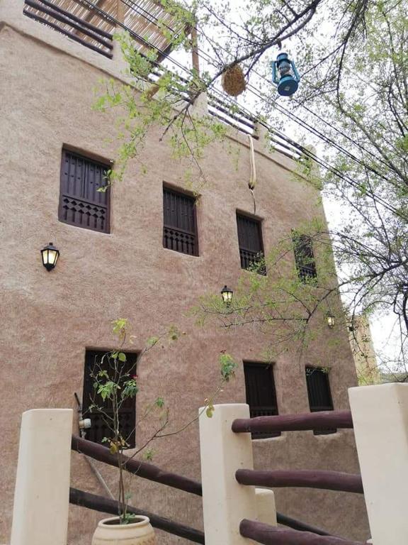a large brick building with windows and a tree at Misfah Heritage House in Misfāh