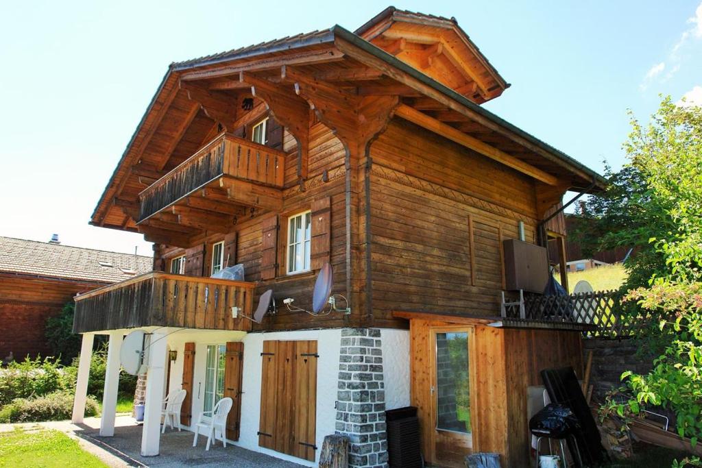 a wooden house with a balcony on top of it at Chalet Mutzli in Gstaad