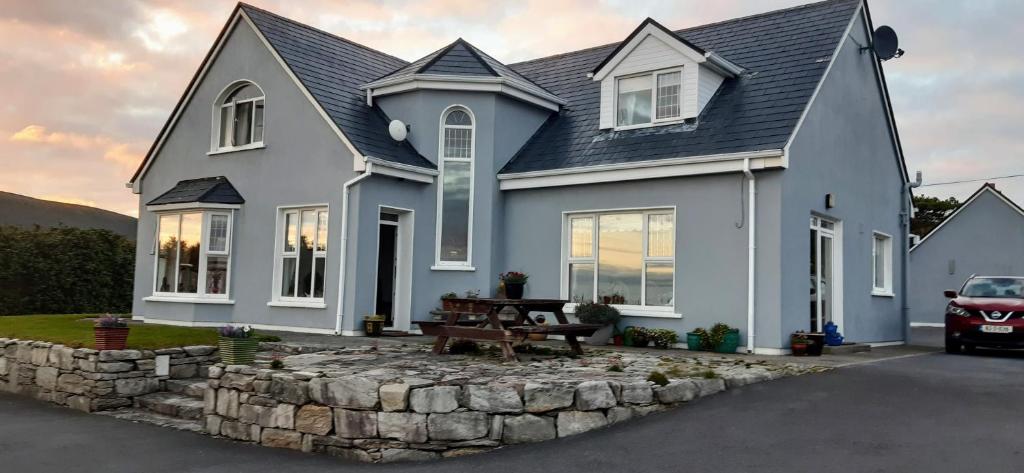 a blue house with a stone retaining wall at Creevagh (Room Only) in Keel