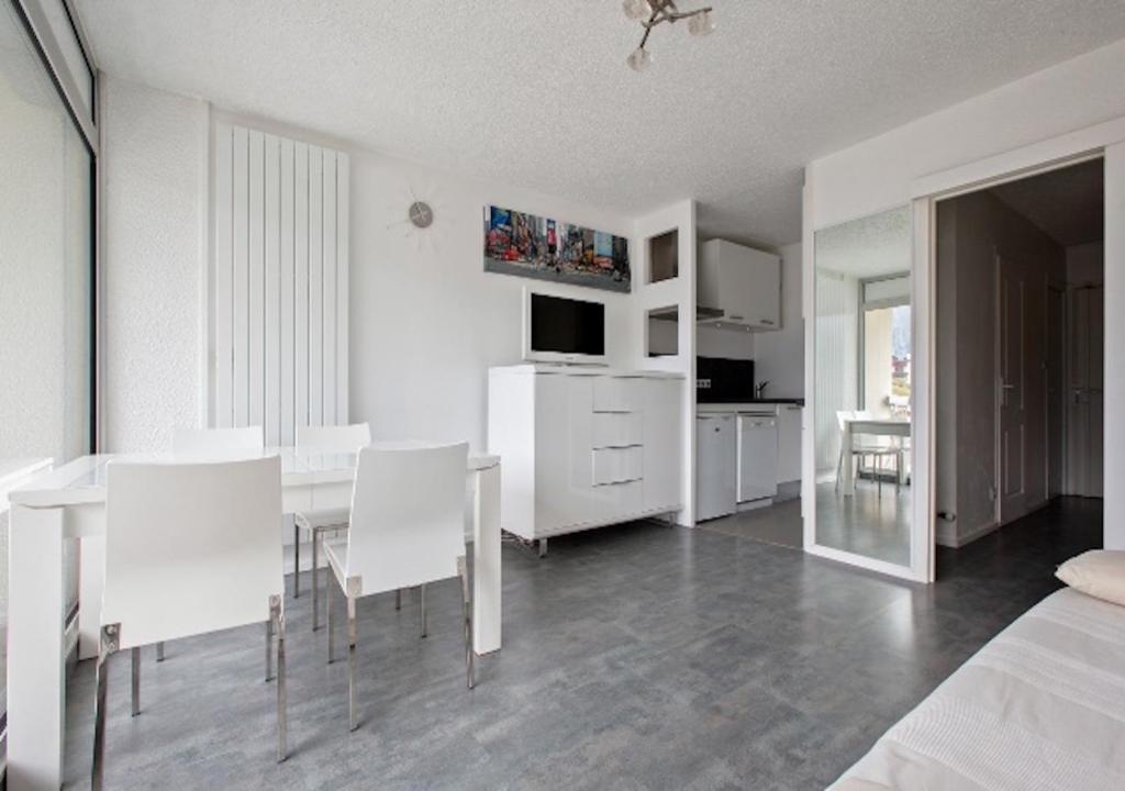 a white dining room with a table and chairs at Appartement 4 personnes (+1) LES 2 ALPES in Mont-de-Lans