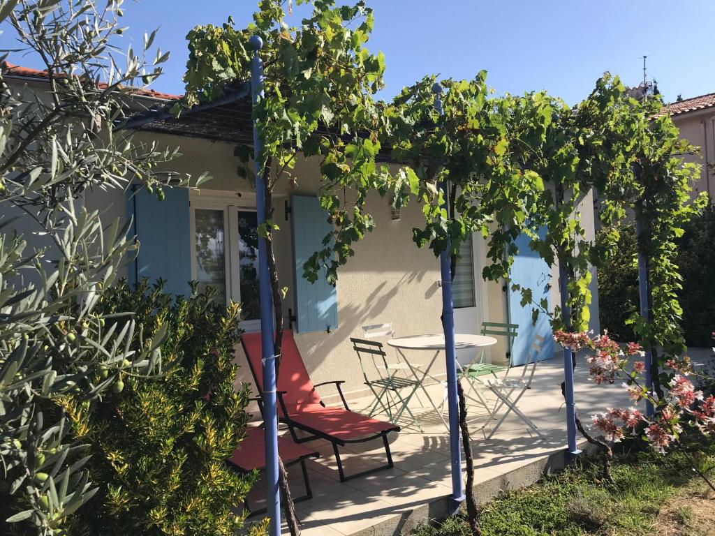 eine Terrasse mit einem Tisch, Stühlen und Bäumen in der Unterkunft Maisonnette El Puy in Moltig les Bains