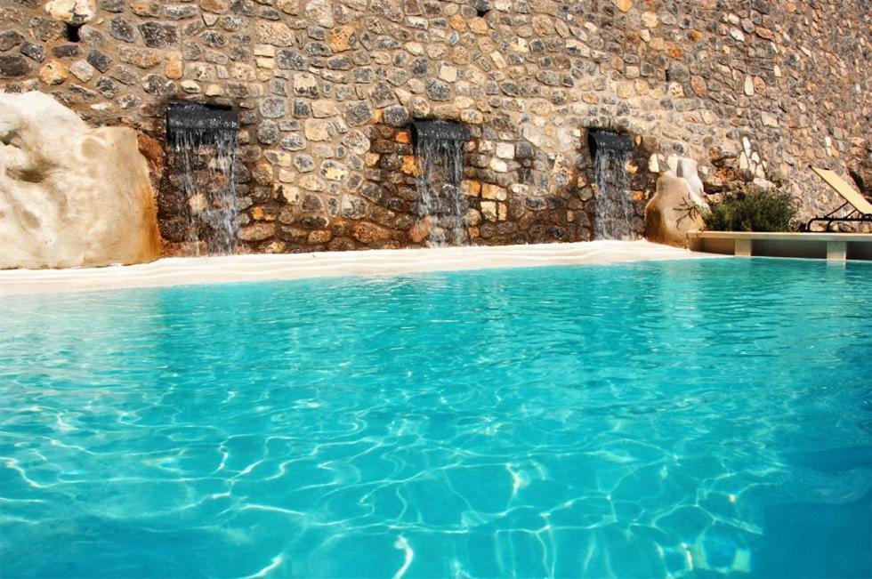 a swimming pool with blue water in front of a stone wall at Loft Apartments by AMALFIVACATION in Amalfi