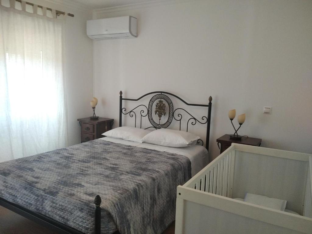 a bedroom with a bed with a blanket and a window at Casa do Outeiro in Penacova