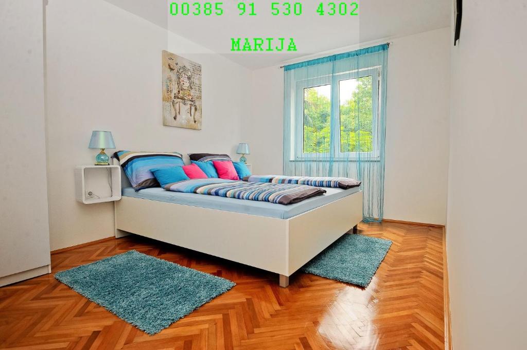 Un dormitorio con una cama con almohadas azules y una ventana en Apartment MB en Rijeka