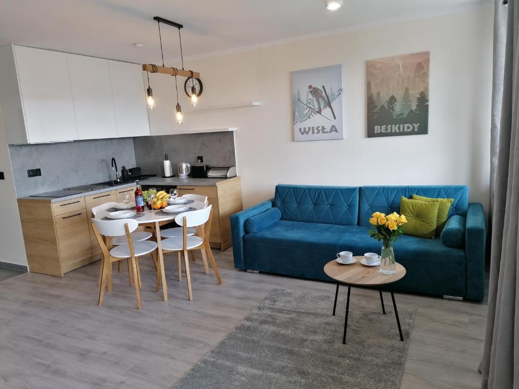 ein Wohnzimmer mit einem blauen Sofa und einem Tisch in der Unterkunft Apartament widokowy ul Bukowa Wisła in Wisła