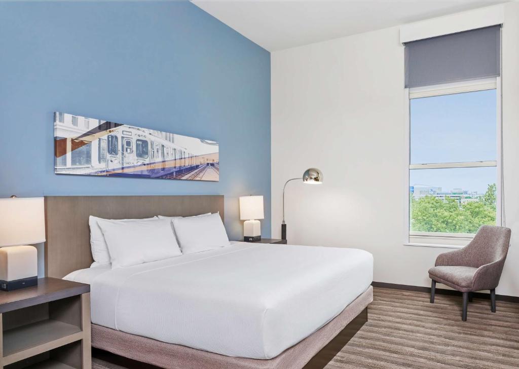 a bedroom with a large white bed and a chair at Hyatt House Chicago Medical/University District in Chicago