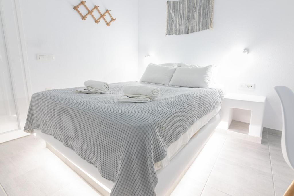 a white bedroom with a bed with a black and white blanket at Carlos Pension in Akrotiri