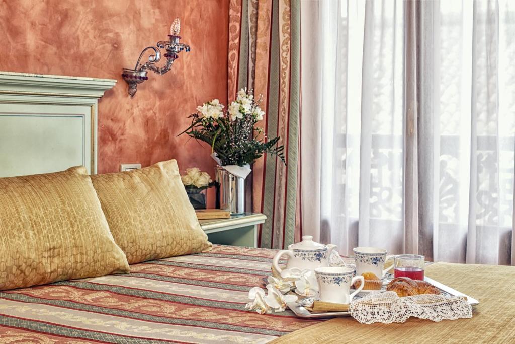 a bedroom with a bed with a tray of food on it at Hotel Firenze in Venice