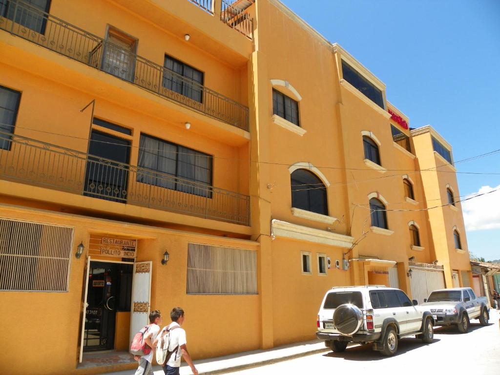 two people walking down a street in front of a building at Hotel Ipsan Nah in La Esperanza