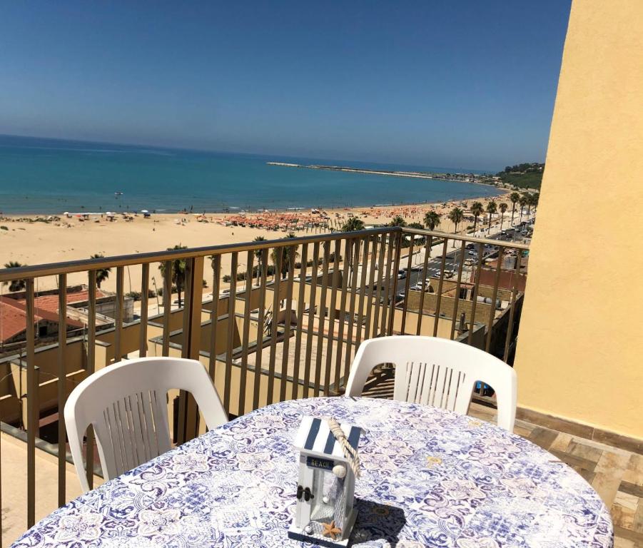 a table and chairs on a balcony with a view of the beach at Terrazza sul Mare Vecchio Pontile in Gela