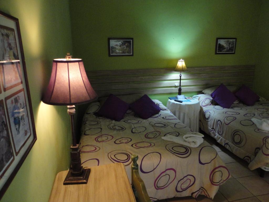 1 dormitorio con 2 camas y una lámpara en una mesa en La Posada de Juan B&B, en Santa Rosa de Copán