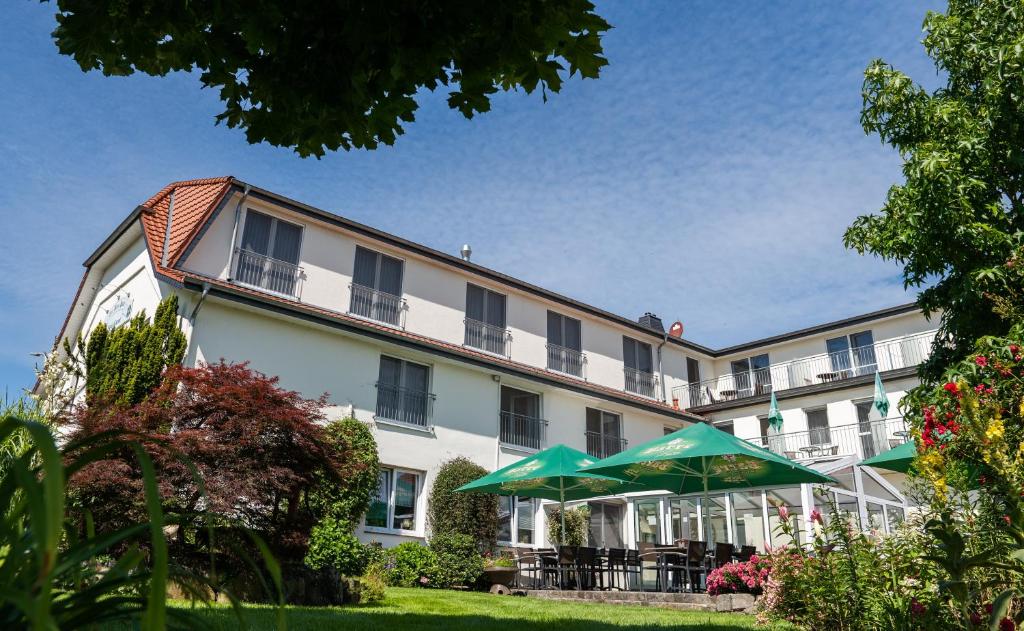 a building with a green umbrella in front of it at Hotel Garni Zur Alten Post in Lembruch