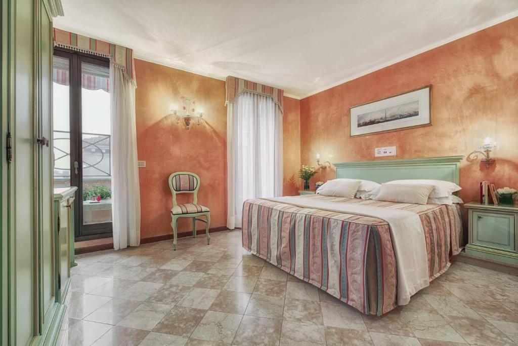 a bedroom with a large bed with orange walls at Hotel Firenze in Venice