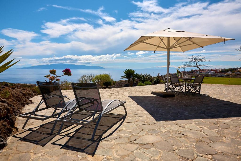 2 stoelen en een parasol op een patio bij Finca el Vinche in Guía de Isora