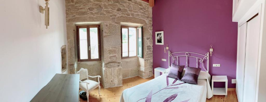 - une chambre aux murs violets et un lit dans un dortoir dans l'établissement A Casa de Feli, à Muros