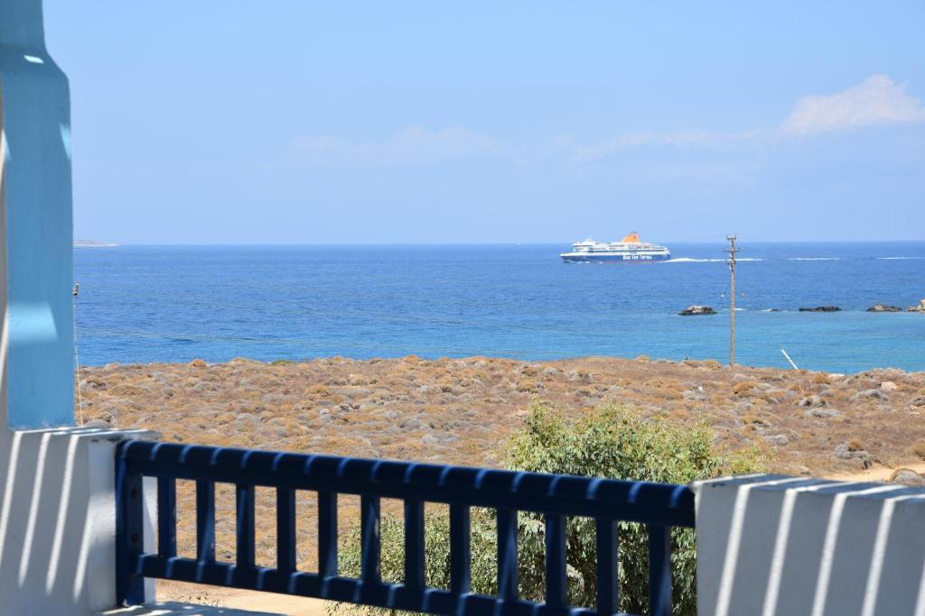 a bench overlooking the ocean with a ship in the distance at Lofos Studios in Agios Prokopios