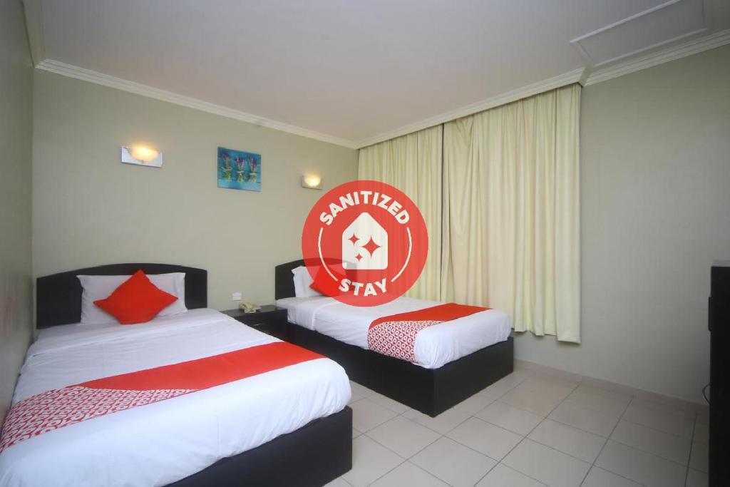 a hotel room with two beds and a red sign at Super OYO 1027 Hotel London in Sandakan