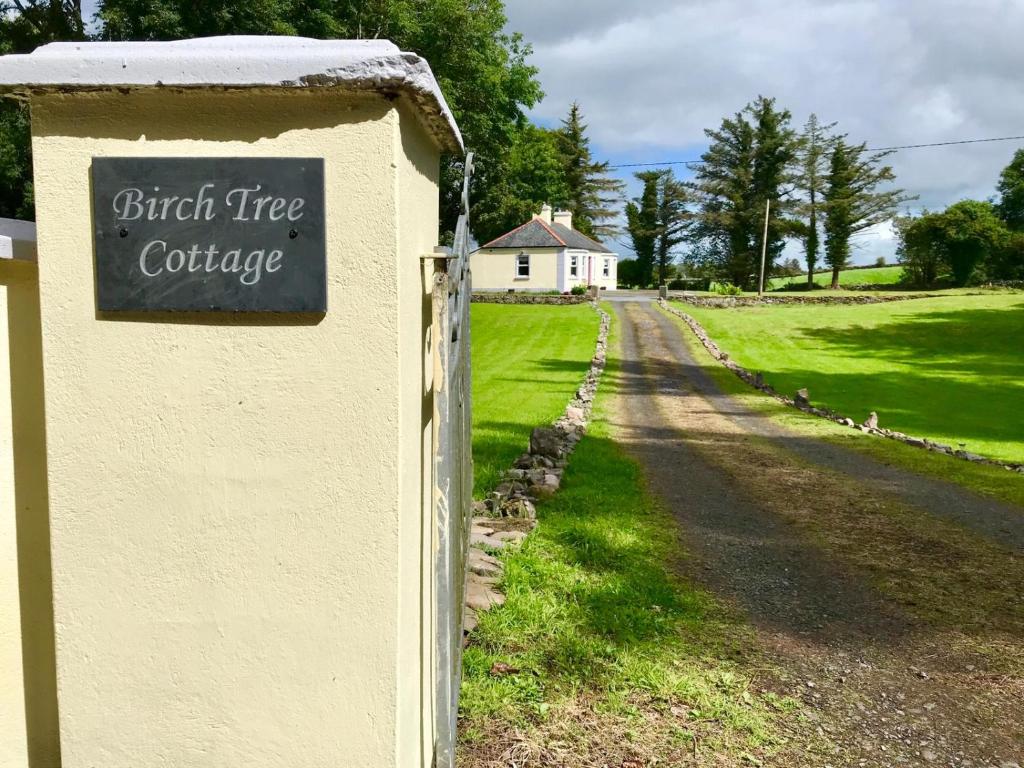 a sign for a brick tree cottage on the side of a road at Birch Tree Cottage in Westport