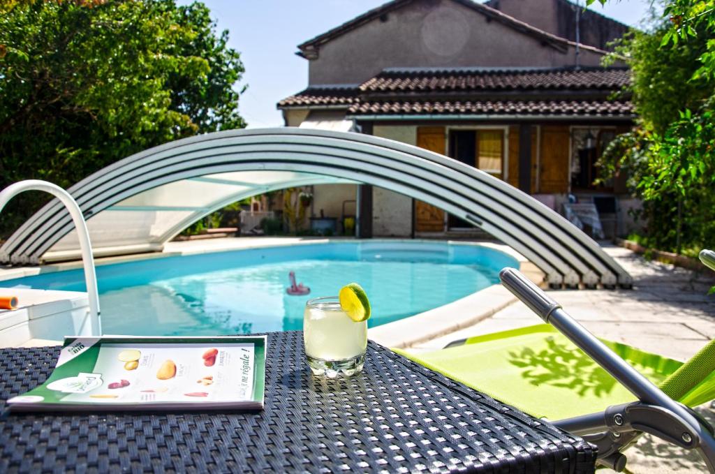 a drink on a table next to a pool at La petite Pierrette in Saint-Benoît-de-Carmaux