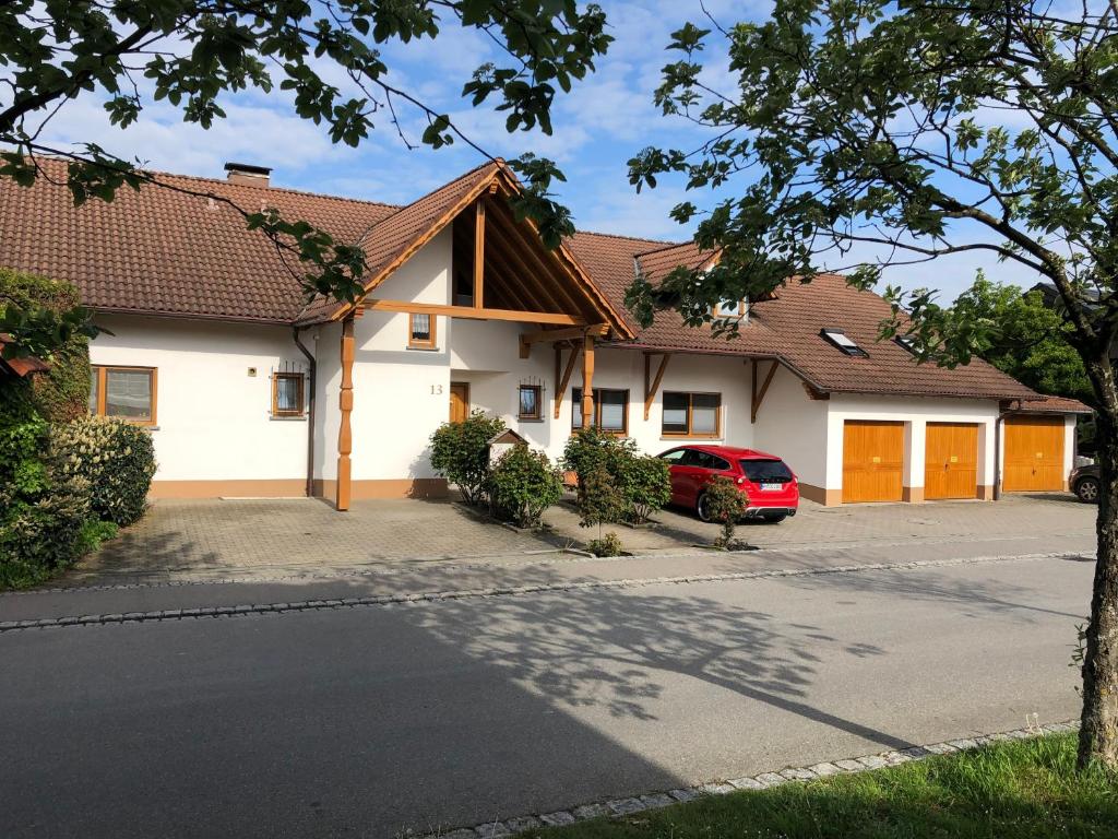 ein Haus mit einem roten Auto, das davor geparkt ist in der Unterkunft Landhaus Monika in Meckenbeuren