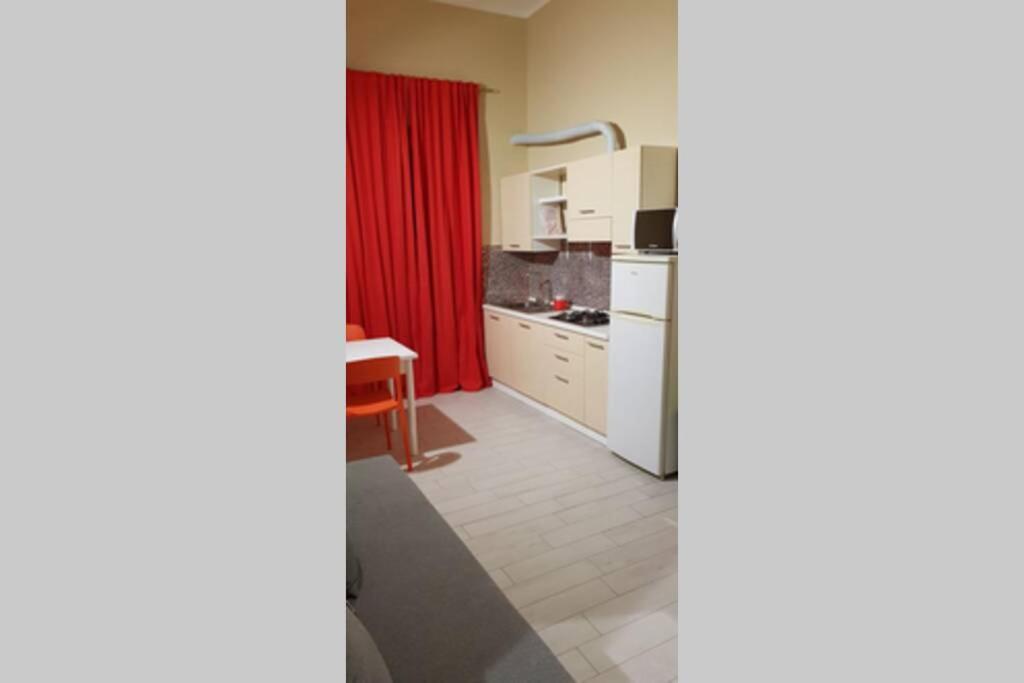 uma pequena cozinha com uma cortina vermelha num quarto em LE ZAGARE abit SOLE a 5 minuti a piedi dal mare e dal centro em Formia