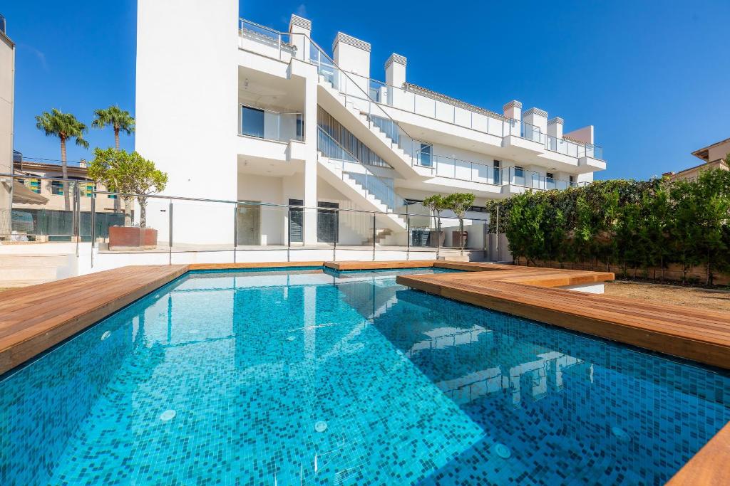 a swimming pool in front of a building at Ático Las Palmeras in Cala Millor