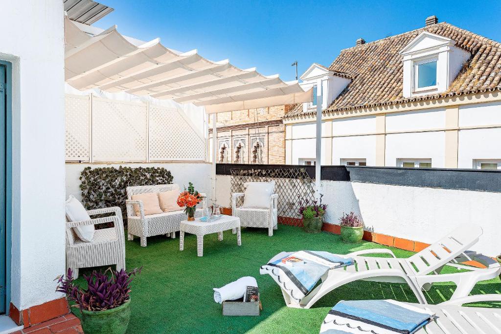een patio met witte stoelen en tafels in een gebouw bij Genteel Home Amor de Dios in Sevilla