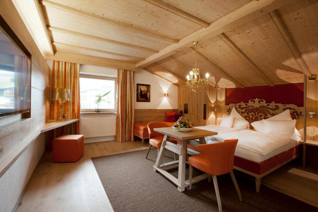 ein Schlafzimmer mit einem Bett und einem Tisch in einem Zimmer in der Unterkunft Minglers Sportalm - Das Gourmet- und Genießerhotel in Kirchberg in Tirol