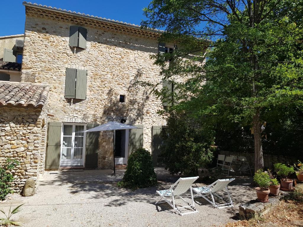 2 chaises et un parasol devant un bâtiment dans l'établissement Mas du Cheval Long, à Sablet